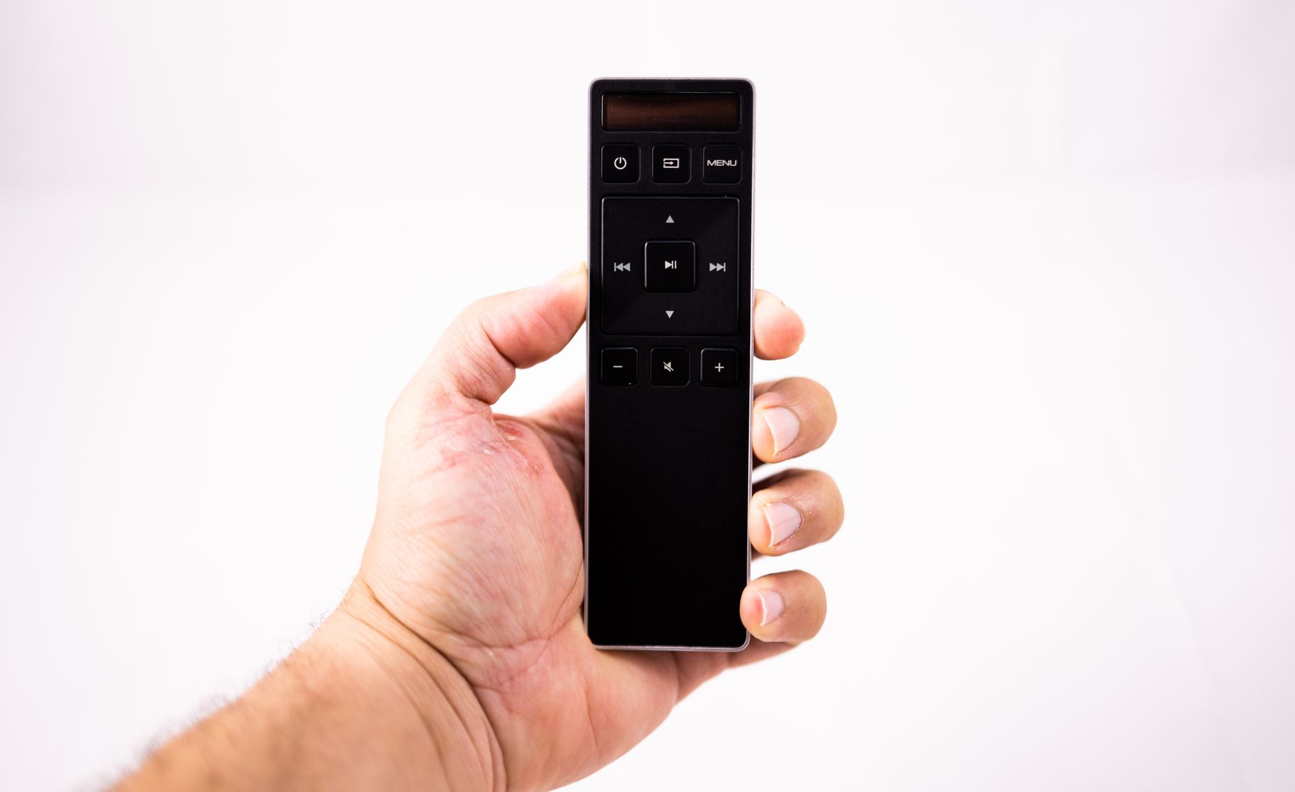 The Best Soundbars for 2026: Elevate Your Home Audio Experience 9 A close-up of a hand holding a remote control, emphasizing user interaction with a soundbar system.