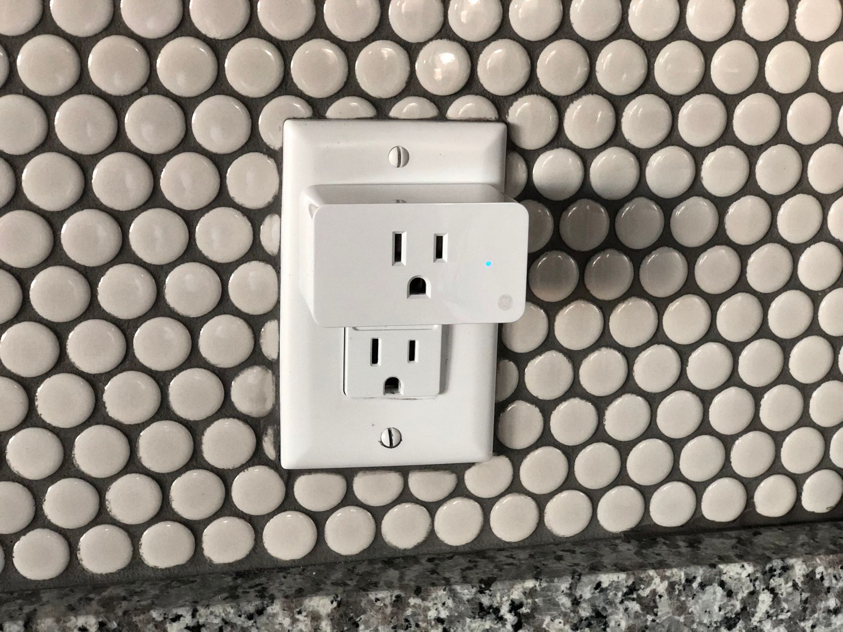 Close-up of a smart power outlet with a device plugged in.