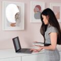 A person happily working at a desk using one of the best standing desk converters for improved posture.