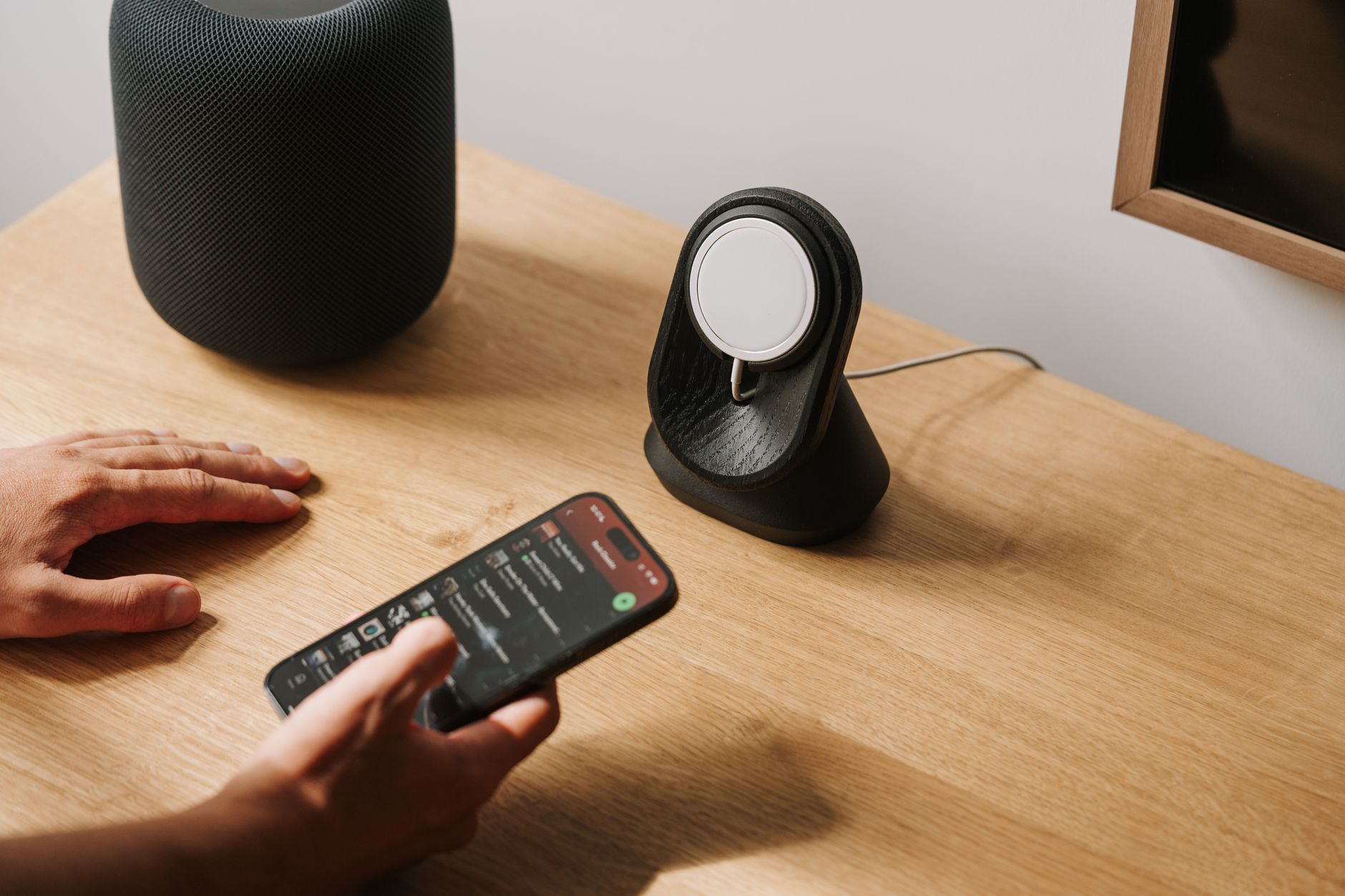 A sleek wireless charging stand holding a smartphone upright on a desk.
