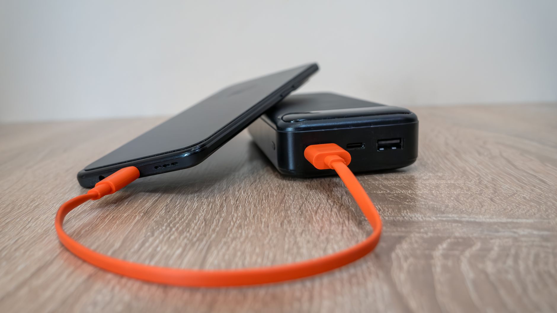 Power Bank vs Power Station: Which Should You Buy in 2026? 2 Person using a power bank to charge smartphone outdoors - power bank vs power station comparison